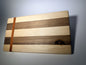 Walnut and maple striped cutting board with straight padauk line — front three-quarter view