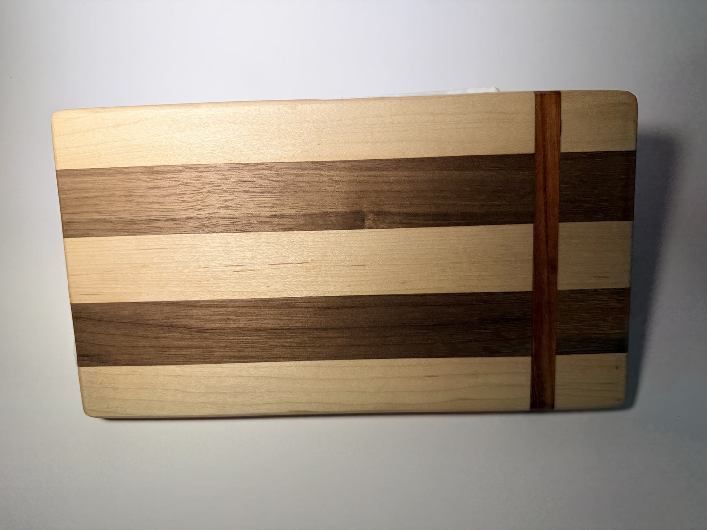 Walnut and maple striped cutting board — angled top view