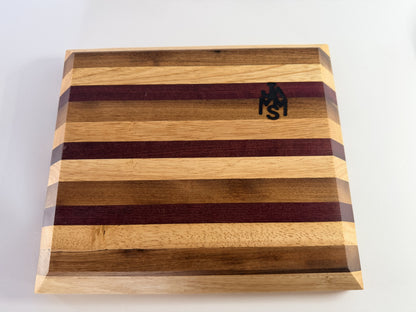 Striped cutting board with beveled edges and JMMS logo — face view
