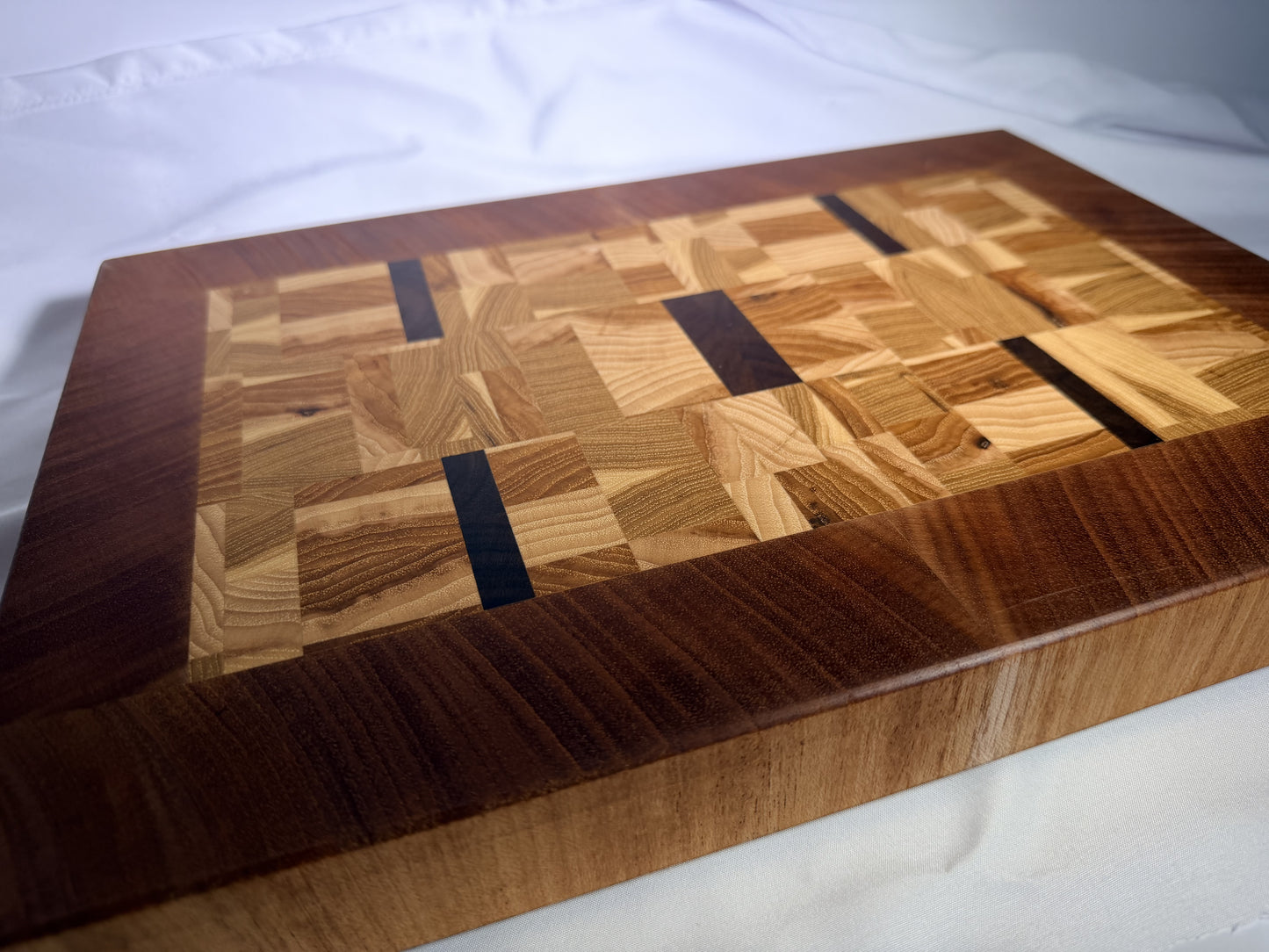 End-grain mosaic cutting board with mahogany border — front three-quarter view