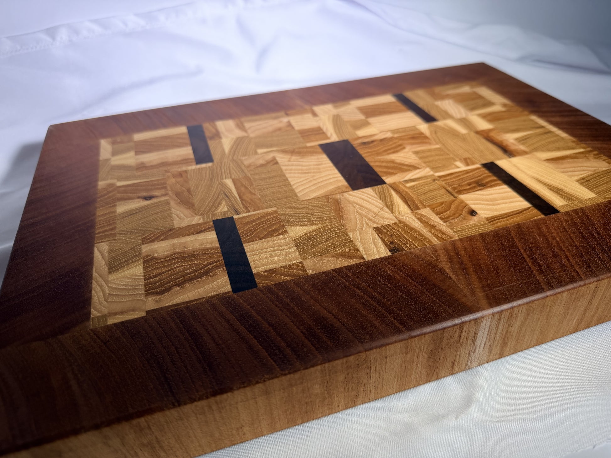 End-grain mosaic cutting board with mahogany border — front three-quarter view