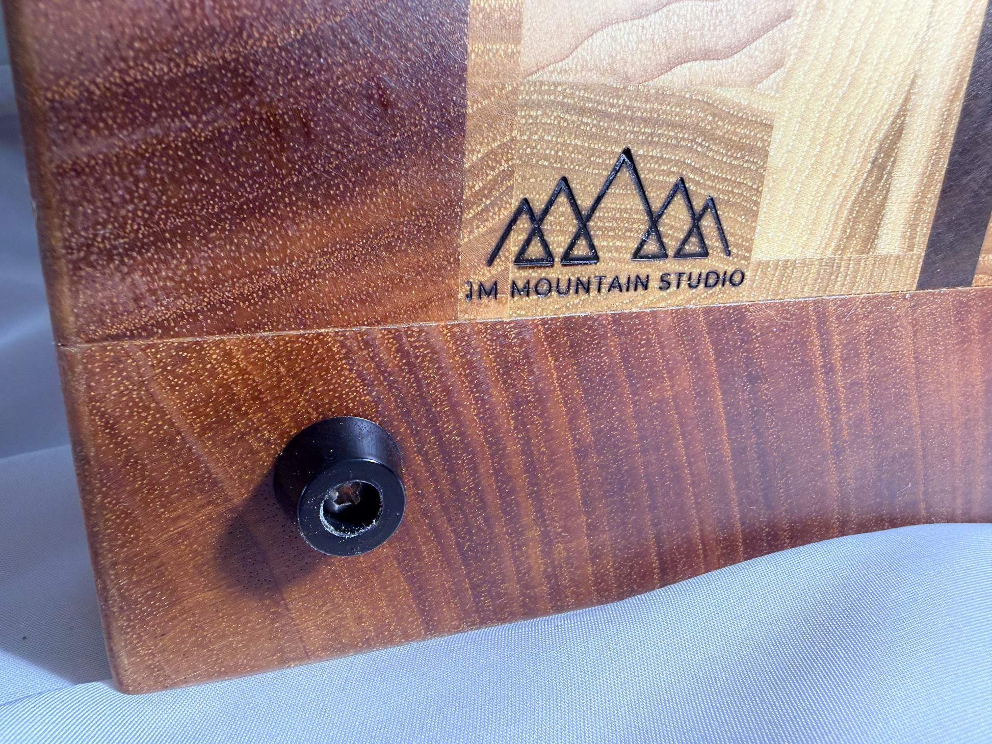 JM Mountain Studio branded logo on mahogany — close-up