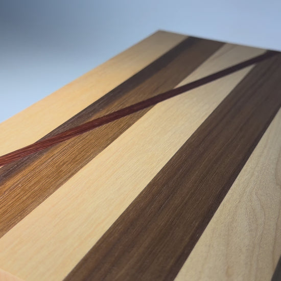 Walnut and maple cutting board with diagonal padauk line — rotating view