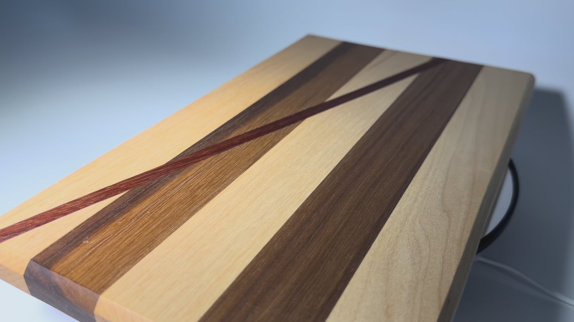 Walnut and maple cutting board with diagonal padauk line — rotating view