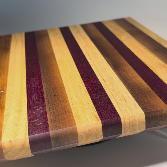 Striped cutting board with purpleheart and walnut — rotating view